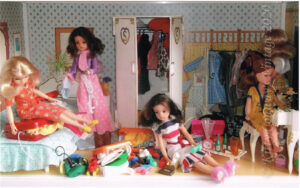 1970s and 80s Sindy dolls search through a messy bedroom to find items to pack in bulging suitcases.
