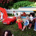 Vintage Sindy dolls stand outside their caravan on a Sindy campsite while Paul unloads a case from the red MG next to an orange tent